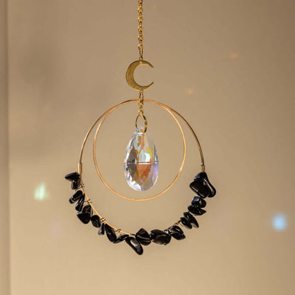 Hanging obsidian quartz crystal suncatcher in sunlight making rainbow