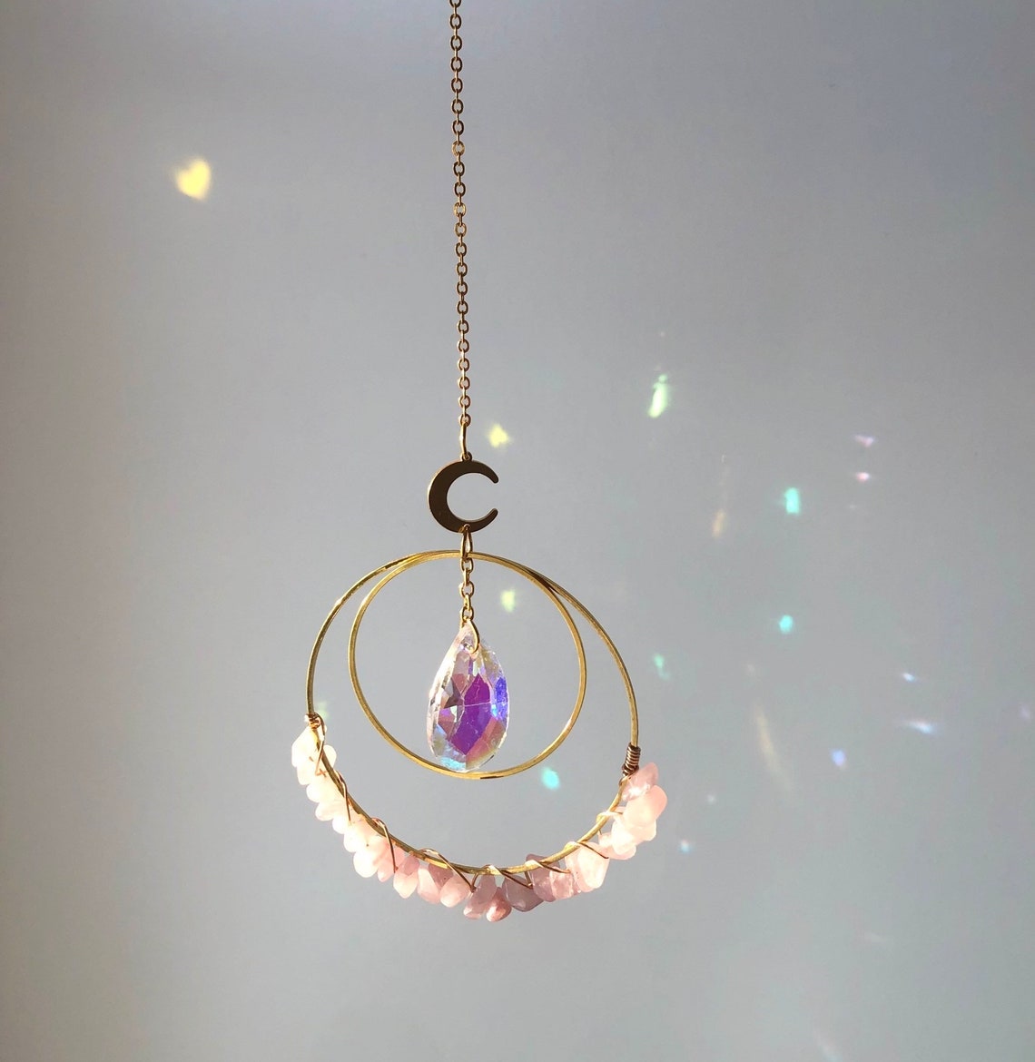 Hanging round rose quartz crystal chips suncatcher in sunlight